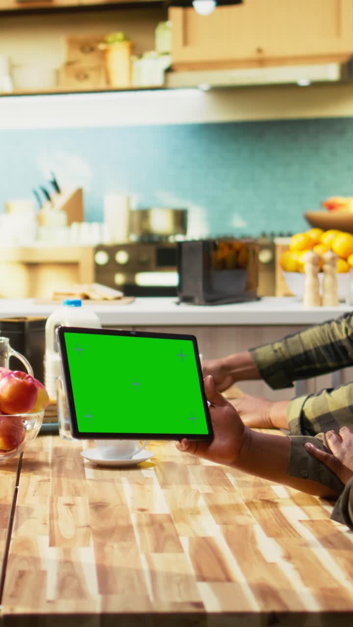 Vertical Video Green screen tablet next to parents and kids sharing breakfast in the kitchen