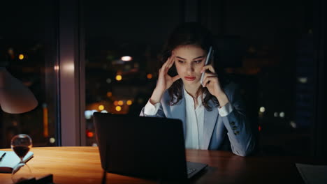 overwhelmed worker talking smartphone sitting office night close up. tired woman