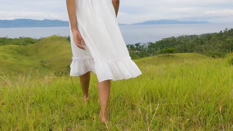 female in white dress walking barefooted on the hills