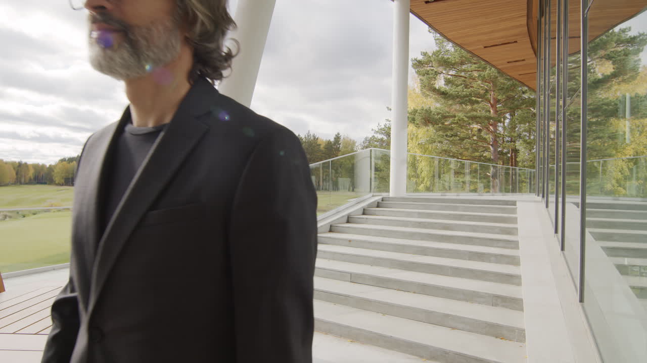 A professional man walks down modern outdoor stairs overlooking a golf course