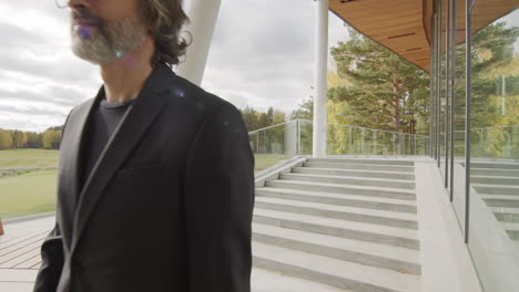 a professional man walks down modern outdoor stairs overlooking a golf course