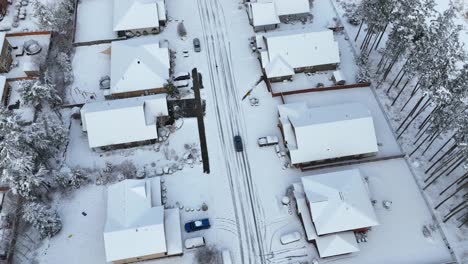 Toma-Aérea-De-Un-Vehículo-Todoterreno-Conduciendo-Por-Un-Vecindario-Cubierto-De-Nieve