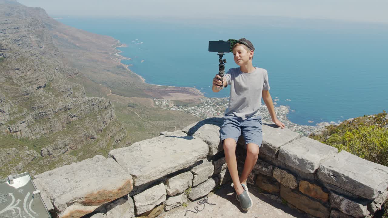 젊은 여행 블로거 소년, 창의적인 아이들, 드폰 앞에서 포즈를 취하는 소년, 여행에 관한 영화를 찍는 소년.