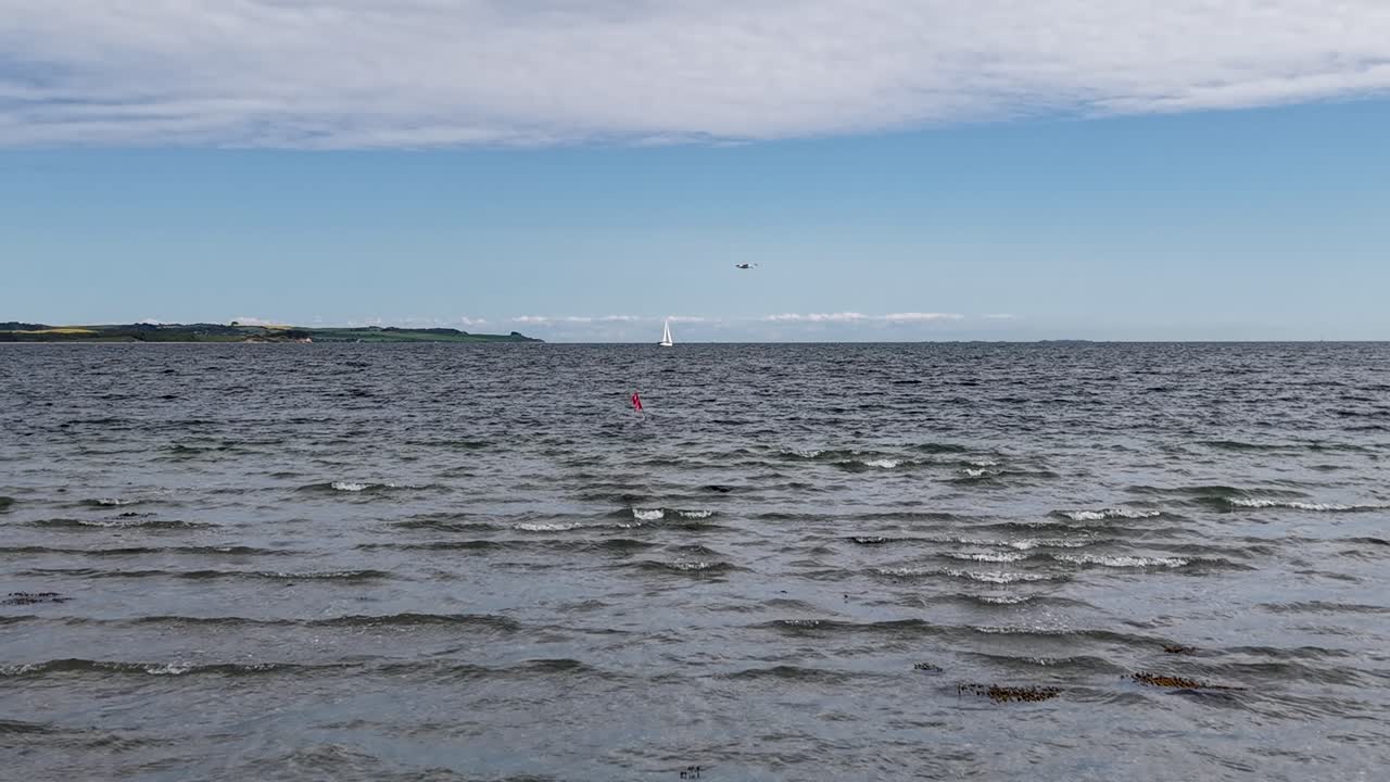 Aerial drone footage of choppy ocean waves under a cloudy sky with horizon in the distance