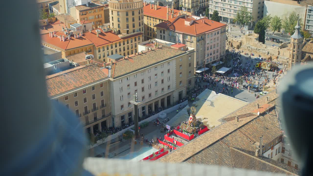Hundredvis af mennesker tilbyder blomster ved statuen af Jomfru Maria på en platform på Plaza del Pilar under Fiestas del Pilar i Zaragoza, Aragon, Spanien