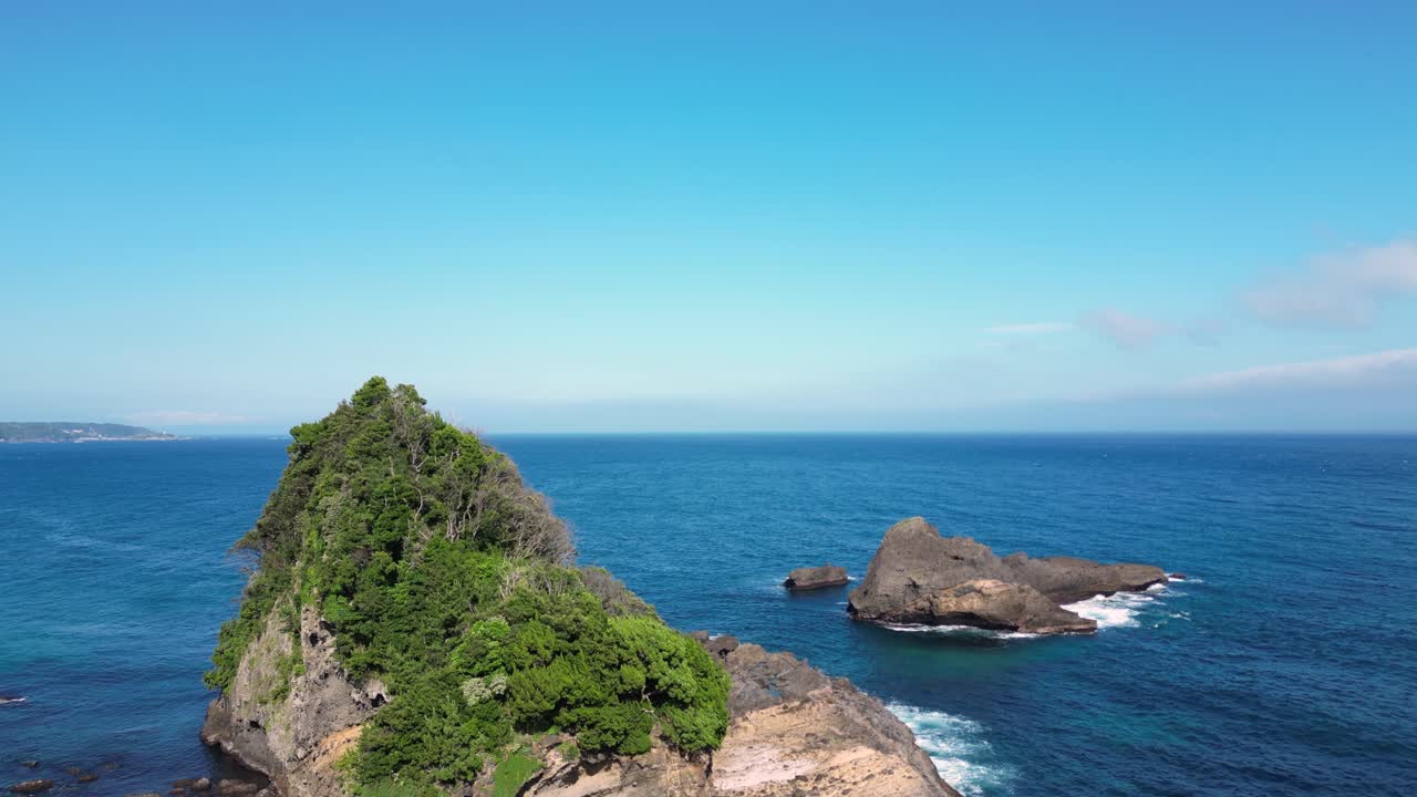 Drone slowly rising above stone cliffs in blue ocean