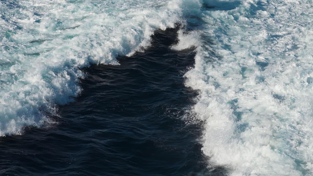 Torrential, splashing water trails left by the passing catamaran ferry