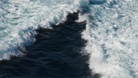 torrential, splashing water trails left by the passing catamaran ferry