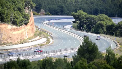 Coches-Circulando-Por-Una-Sinuosa-Autopista-Rodeada-De-árboles-Verdes