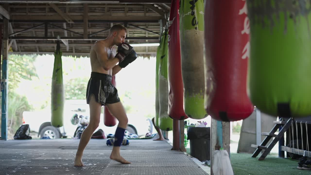 Man training Muay Thai with a punching bag in a gym