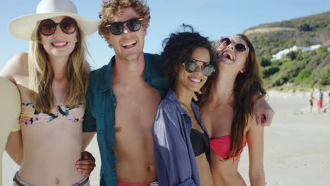 mixed race group of friends smiling at camera for a portrait on the beach