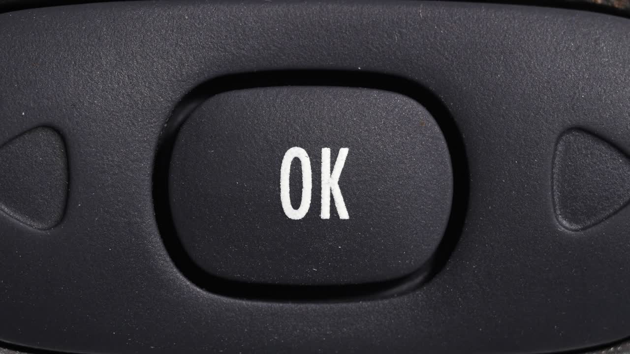 Close up of finger pressing OK button on dark control panel