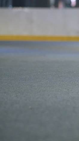 vista enfocada de las piernas de la dama preparándose para patear la pelota de fútbol contra la pared durante la práctica, la escena captura el movimiento y el control en la superficie de juego texturizada bajo iluminación artificial equilibrada