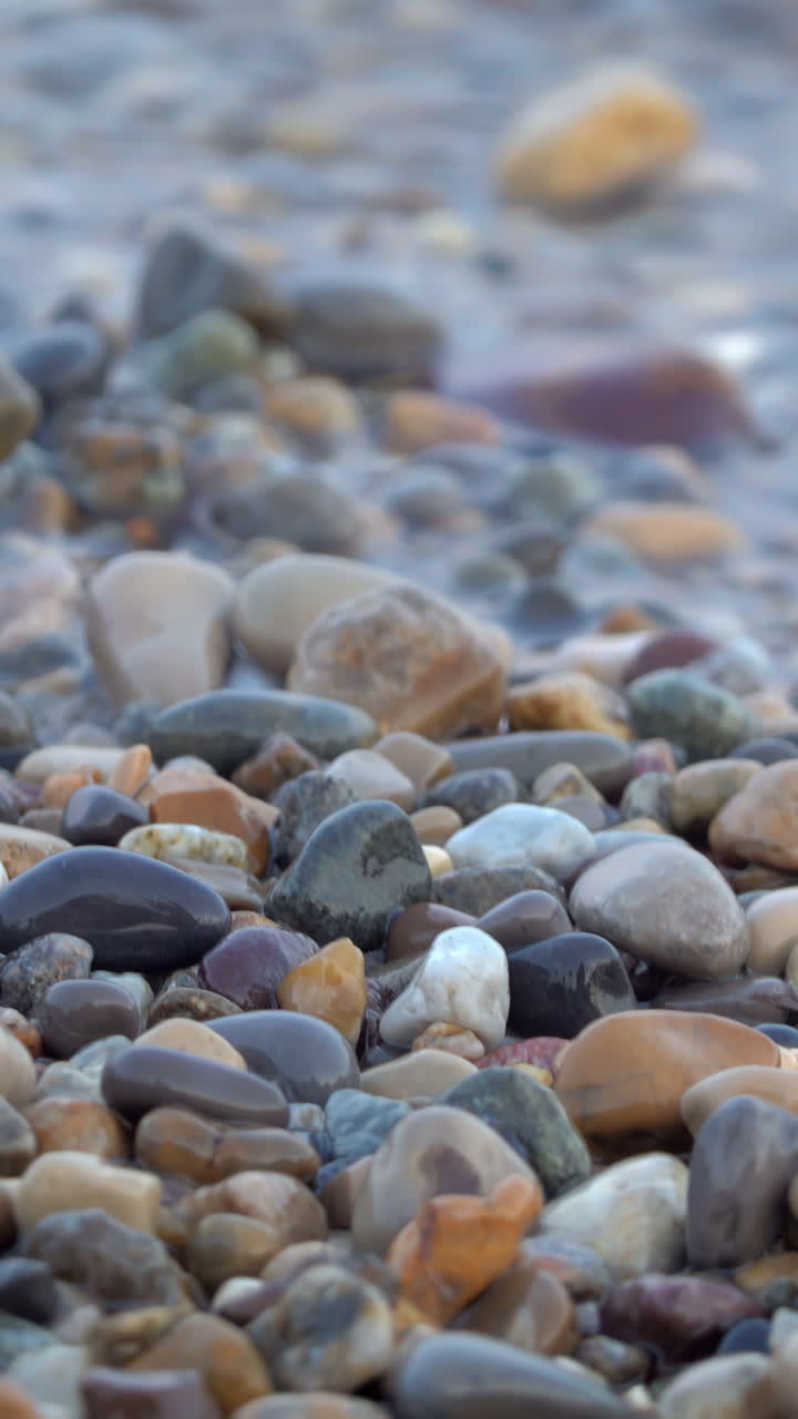 Close up of waves hitting the shore on a stone beach in Antibes, France. Vertical