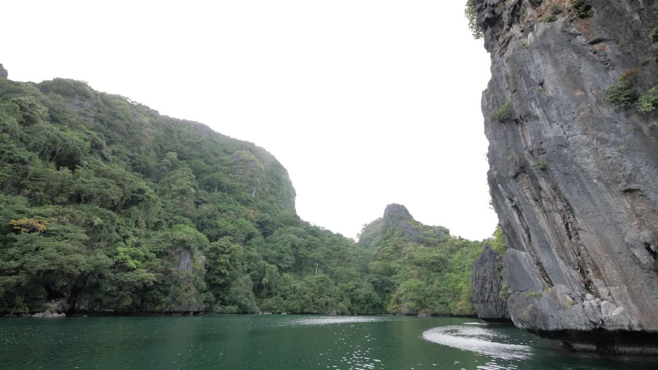 tiro de muñeca en cámara lenta navegando en la famosa gran laguna rodeada de acantilados de piedra caliza en el nido, palawan, filipinas