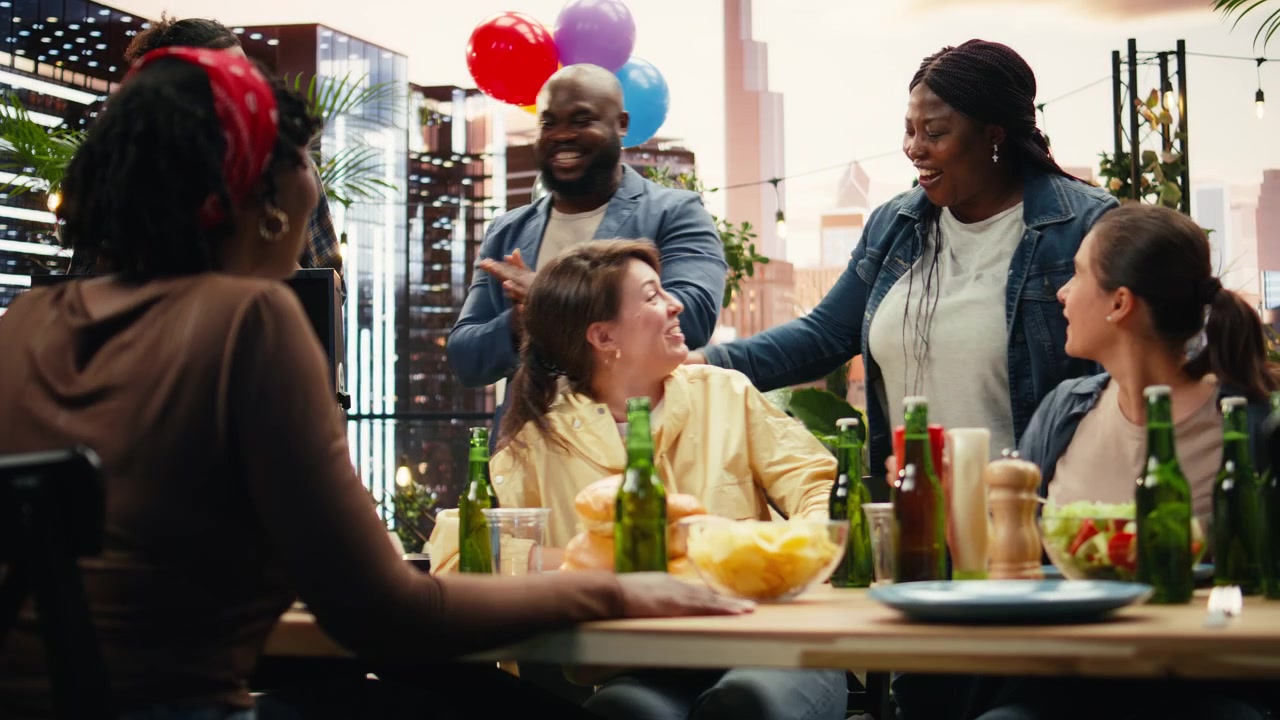 Woman arriving at rooftop BBQ party and hugging friends as greeting