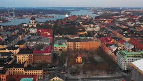 Forward-flying-drone-above-various-houses-in-neighbourhood-close-to-Church-of-Catherine-and-surrounding-park-with-cemetery.-Stockholm,-Sweden