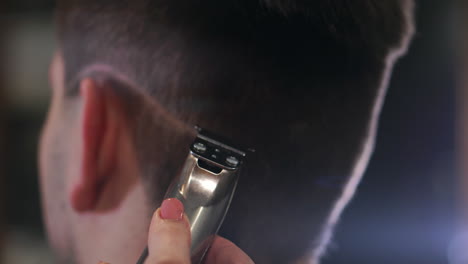 Friseur,-Der-Männliche-Haare-Mit-Elektrorasierer-In-Der-Schönheitsschule-Schneidet.-Frau-Friseur-Macht-Männlichen-Haarschnitt-Mit-Haarschneidemaschine-Im-Friseursalon-Nahaufnahme