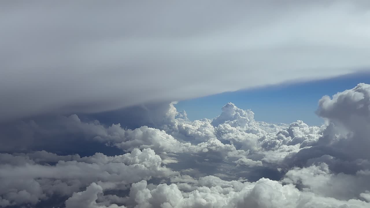 Real time flight through s stormy sky surroended by threatening and massive cumulonimbus storm clouds, as seen by the pilot from a jet cockpit, with a blue sky at the back. Ultra-realistic 4K