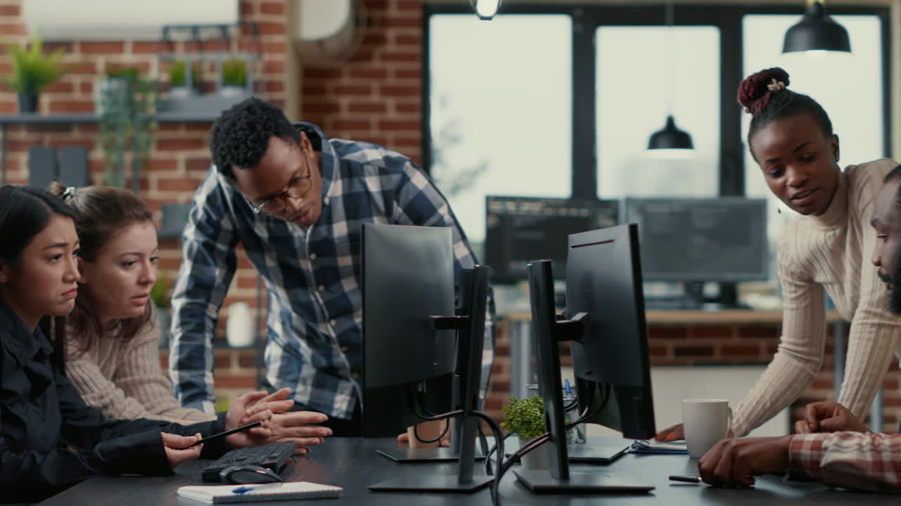 Mixed team of programmers brainstorming ideas for new cloud computing user interface looking at running code