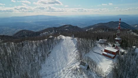 aerial 4k drone footage of a tv and radio communication center on the top of the mountain in the winter time