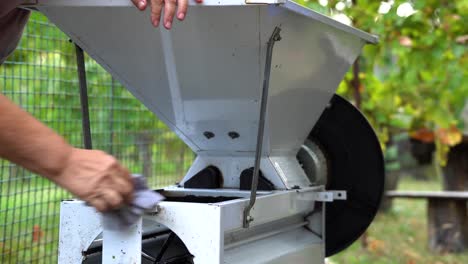 Older-caucasian-woman-cleaning-grape-crusher-after-harvest-in-the-vineyard