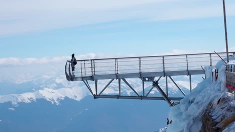 person walking on a high altitude bridge with amazing mountain views