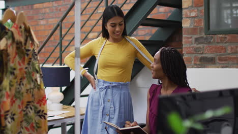 mujeres diseñadoras de moda felices y diversas usando las medidas de cinta discutiendo el trabajo en la oficina