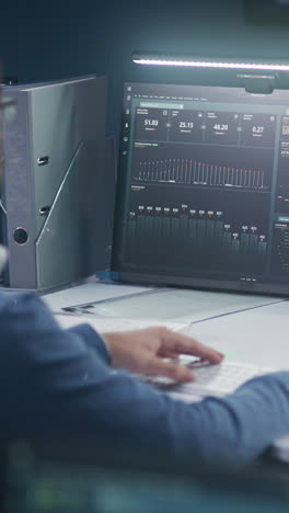 man working on a computer with multiple monitors displaying data charts and graphs