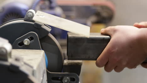 extreme hands close up of skilled technician engineer polish a piece of metal on a polishing machine in a factory