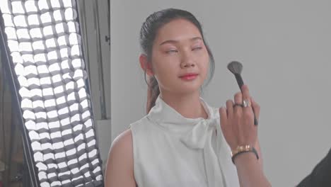 makeup artist applying blush to model