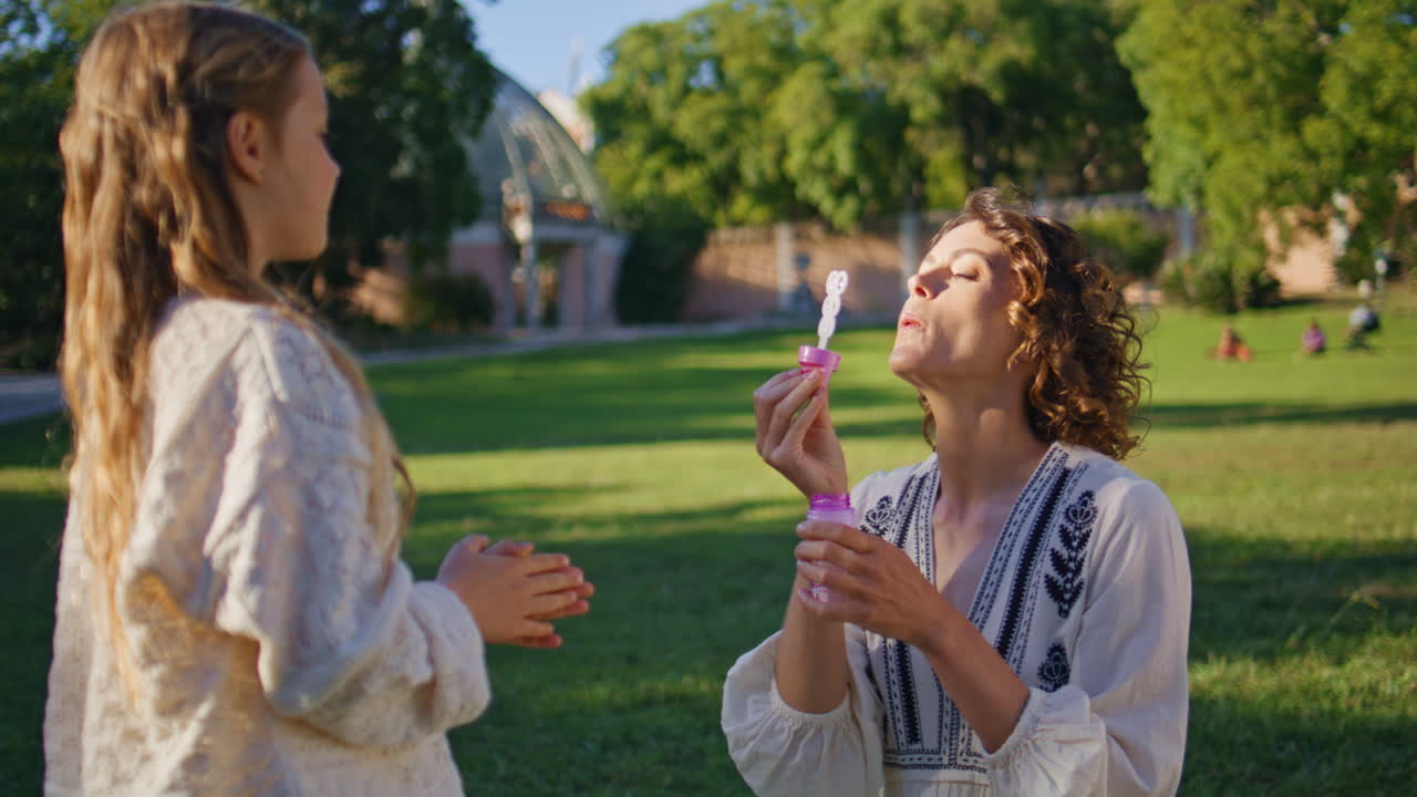 Joyful family blowing soap bubbles in sunshine park closeup. Happy leisure time