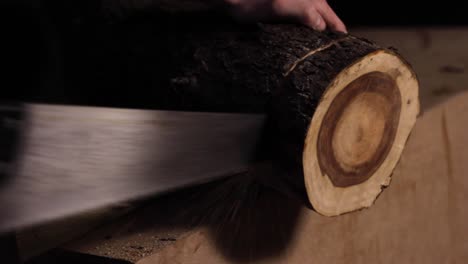 Manually sawing a log of wood with bare hands in a woodworking carpentry workshop