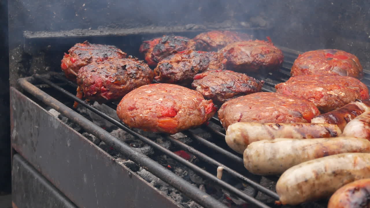 Primo piano di uno chef che gira le salsicce, barbecue fumante