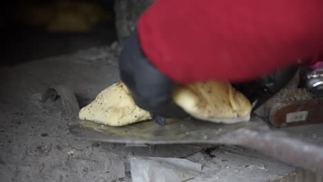 un panadero colocaba flaouna cruda en un horno griego tradicional para hornear