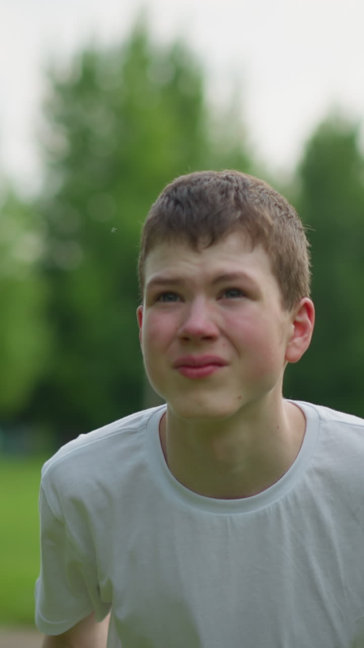 un niño se centra atentamente mientras dirige una pelota de fútbol lejos en un campo cubierto de hierba, con una vista borrosa de un poste de la portería y árboles exuberantes en el fondo