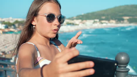 chica feliz tomando una selfie afuera. mujer joven agitando la mano al celular afuera.
