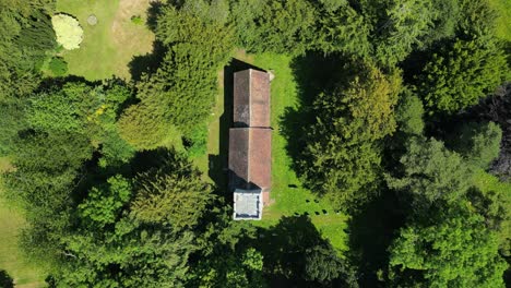 A-top-down-push-in-shot-towards-Lady-Magdalene-church-in-Denton,-Kent,-surrounded-by-greenery