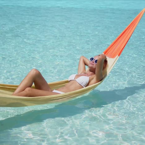 Relaxed-woman-lying-on-hammock-over-pool