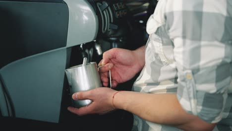 barista espresso preparation. coffee shop worker steams milk for a hot latte. latte art coffee