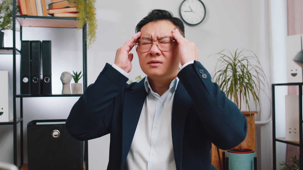 Tired asian business man suffering from headache problem tension migraine stress at home office
