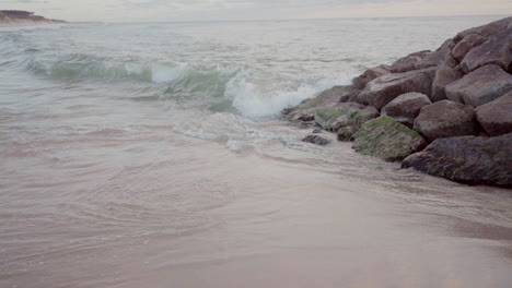 sea water hitting rocks on a beach, creating gentle waves and splashes