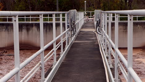 a chocolate-colored sewage bath churns below the center walkway of a wastewater treatment plant, showcasing the industrial flow and dynamic treatment process