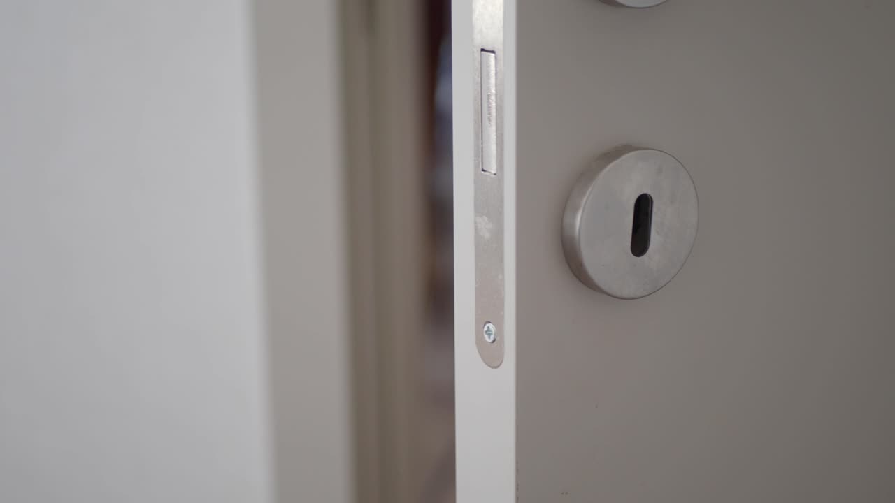 Close up of a white door with a silver handle and keyhole