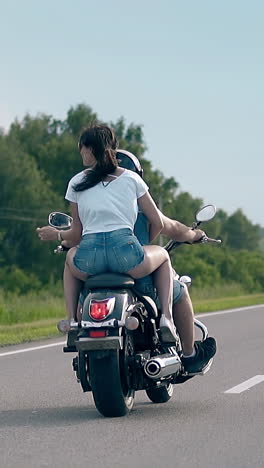 couple riding a motorcycle on a country road