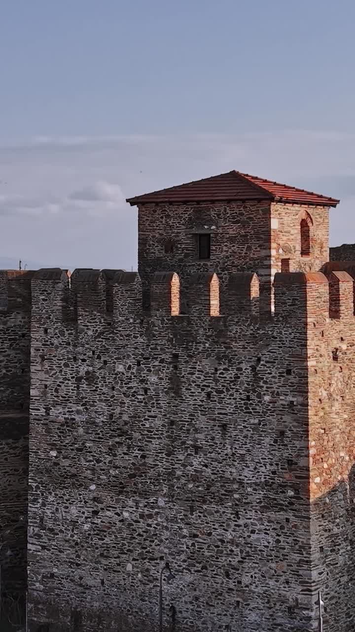 Vecchia fortezza si erge in Grecia sotto un cielo sereno con vista su una città in lontananza.