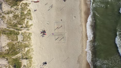 antena: jóvenes juegan voleibol en una arena cerca del mar en nida