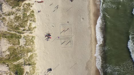 aerial: young people plays volleyball on a sand near sea in nida