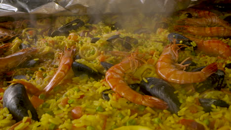 close up shot over a paella dish with prawns and tiger shrimp in a big pan