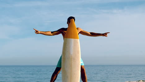 hombre atractivo escondiéndose detrás de su tabla de surf